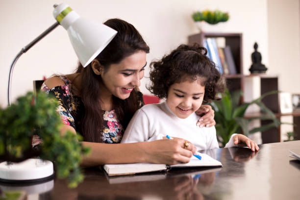 Mother helping daughter with homework Happy mother helping daughter with homework kids learn books stock pictures, royalty-free photos & images