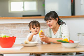 母は彼女の小さな娘がスムージーを作るのを助け、健康的な食事のために彼女を励まします