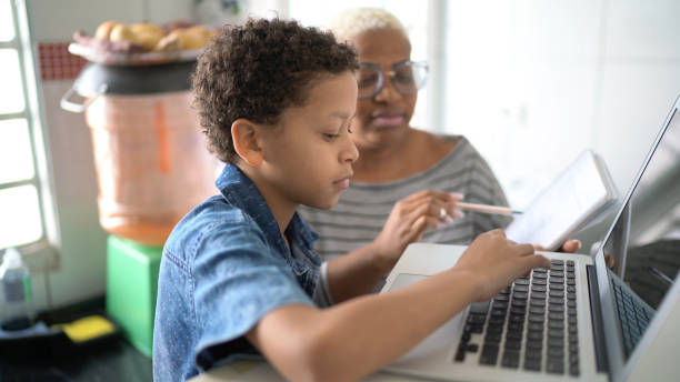어머니는 집에서 온라인 수업에 노트북으로 공부하는 그녀의 아들을 돕는 - 멀리 떨어진 뉴스 사진 이미지