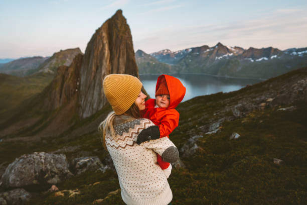 Mother hiking with baby family vacation adventurous travel outdoor in mountains woman with child together trip in Norway recreation healthy lifestyle stock photo