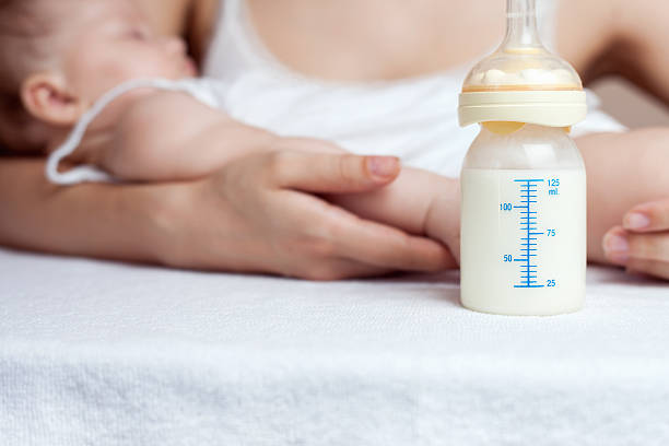 Mother holding a baby and bottle with breast milk Mother holding a baby and bottle with breast milk for breastfeeding at foreground, mothers breast milk is the most healthy food for newborn baby baby formula stock pictures, royalty-free photos & images