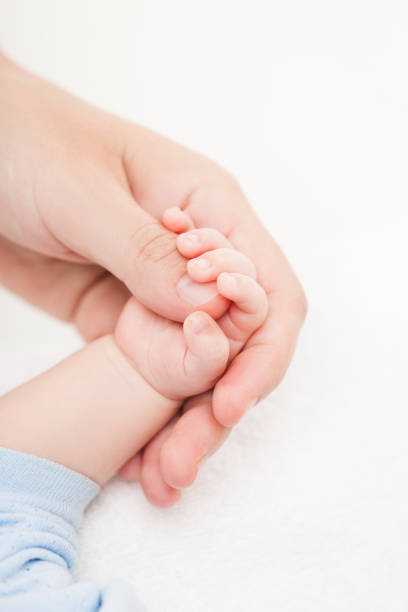 Mother holding newborn baby child little hand with small fingers stock photo