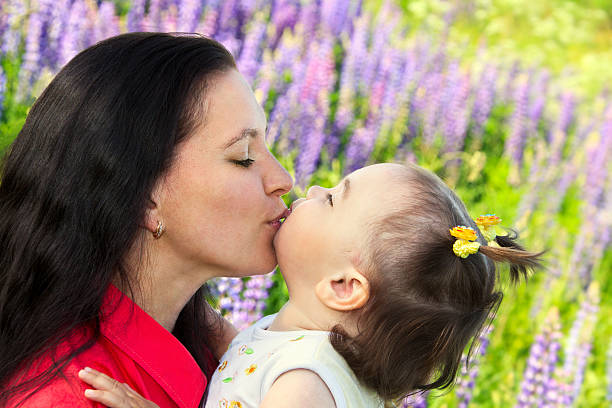 mother kissing her little daughter stock photo