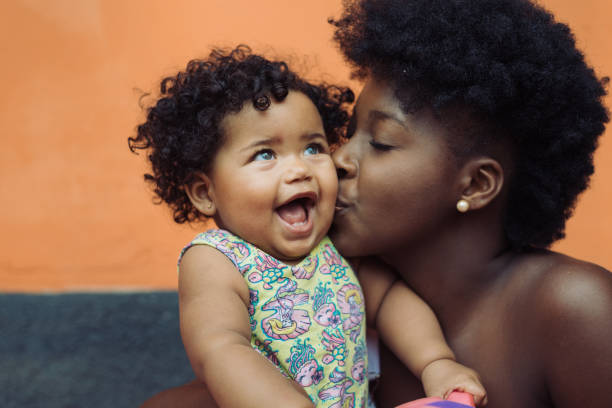 Mother kissing smiling baby girl stock photo