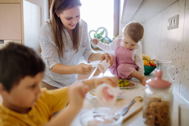 Mother of two little children preparing breakfast in kitchen at home. stock photo