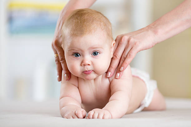 Mother or therapist makes massage to her baby at home stock photo