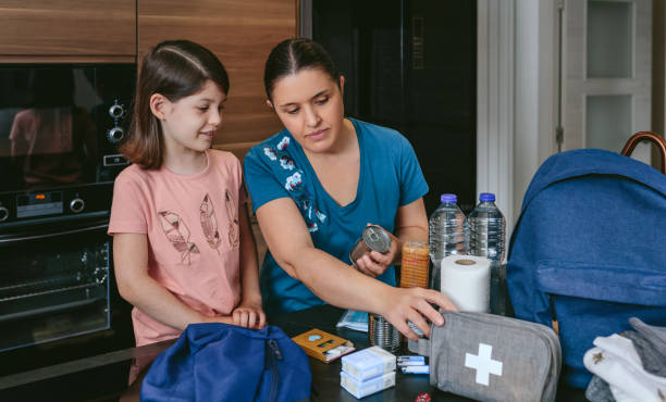 Mother preparing emergency backpack with her daughter stock photo