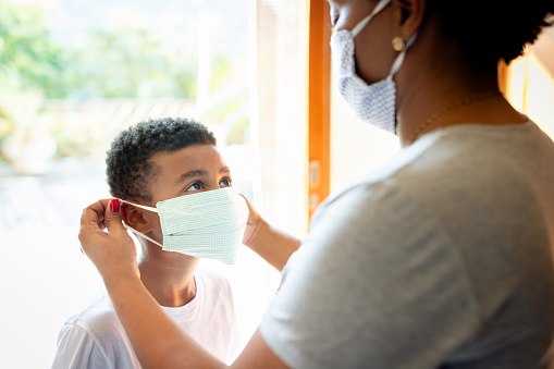 Shot of a woman putting mask on her son