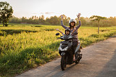 portrait of happy mother raise her arm while riding motorcycle with her daughter