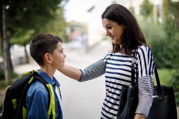 Mother saying goodbye to son in front of school Mother saying goodbye to son in front of school mother and teenage son stock pictures, royalty-free photos & images