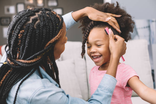 mother styling daughter's curly hair stock photo