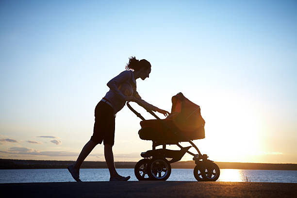 Mother with a stroller Silhouette of  young mother enjoying motherhood carriage stock pictures, royalty-free photos & images