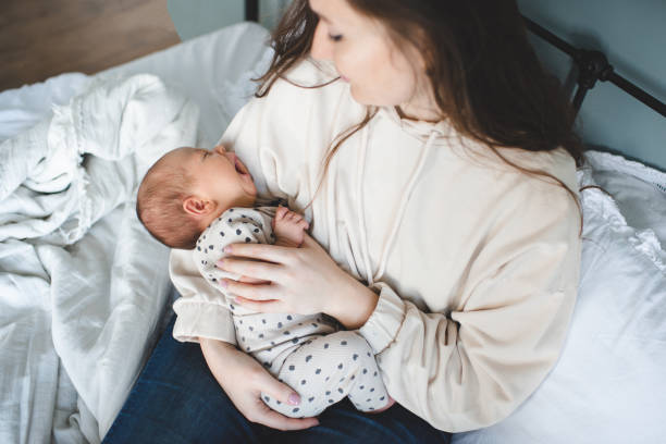 Mother with baby on hands in room in bed stock photo