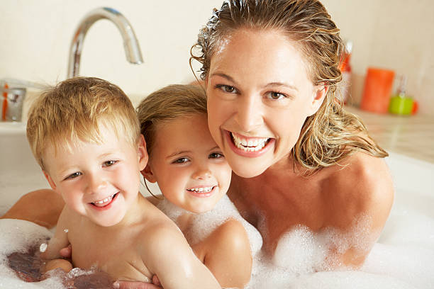 mother with children relaxing in bubble filled bath - woman washing hair stockfoto's en -beelden