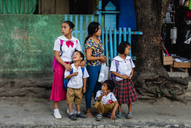 A mother with her children waiting Malay, Philippines - January 11, 2016: A mother and her children, wearing school uniforms, waiting to go to school in Boracay island, on the municipality of Malay, Philippines. philippines girl stock pictures, royalty-free photos & images