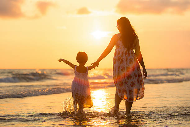 Mother with her daughter on the beach stock photo