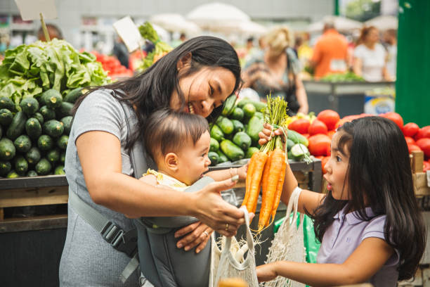 madre con niños comprando en el mercado - farmers market fotografías e imágenes de stock