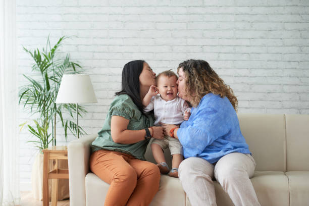 Motherhood Mothers kissing their happy laughing child on both cheecks gay person stock pictures, royalty-free photos & images
