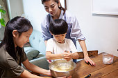 タブレットでレシピを見ながらお菓子を作る母親と子供