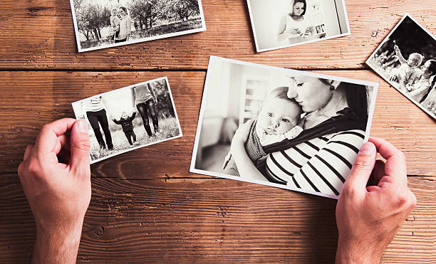 Mothers day composition. Black-and-white pictures, wooden backgr Mothers day composition. Hands of unrecognizable man holding  black-and-white photos. Studio shot on wooden background. human body part photos stock pictures, royalty-free photos & images