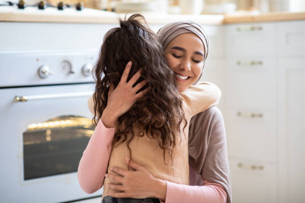 Mother's Day. Loving Little Girl Hugging Islamic Mommy In Kitchen At Home Loving Little Girl Hugging Islamic Mommy In Kitchen At Home, Greeting Her With Mother's Day. Muslim Woman In Hijab Cuddling Her Kid With Closed Eyes And Smiling, Closeup Shot With Copy Space hot middle eastern girls stock pictures, royalty-free photos & images