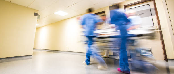 Motion blurred view of hospital personnel pushing gurney down corridor stock photo