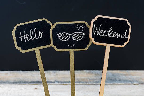Motivational message Hello Weekend written with chalk Motivational message Hello Weekend written with chalk on wooden mini blackboard labels, defocused chalkboard and wood table in background weekend activities stock pictures, royalty-free photos & images