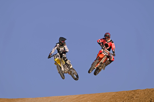 Two Motocross Racers Flying Through the Air 