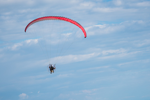 Motor paraglider flying in blue sky