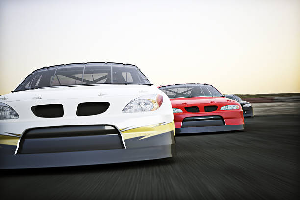 Motor sports racing Front view of auto racing race cars racing on a track with motion blur.  racecar stock pictures, royalty-free photos & images