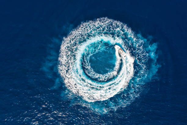 Motorboat forms a circle of waves and bubbles with its engines Motorboat forms a circle of waves and bubbles with its engines over the blue sea motorboat stock pictures, royalty-free photos & images