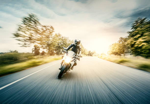 Motorcycle in blurred motion Woman drives on a motorcycle on a country road riding stock pictures, royalty-free photos & images