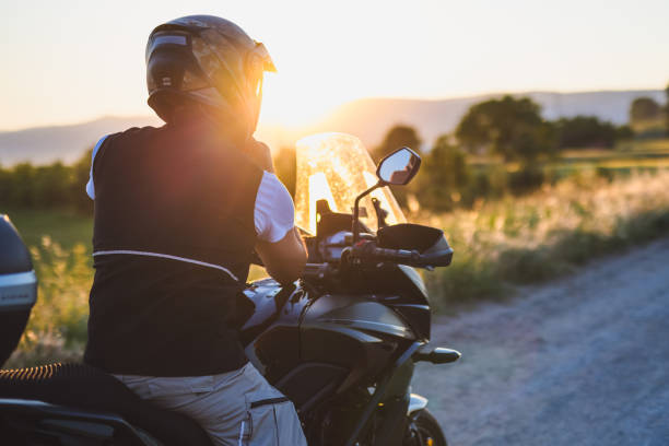 Motorcyclist on the country road at sunset stock photo
