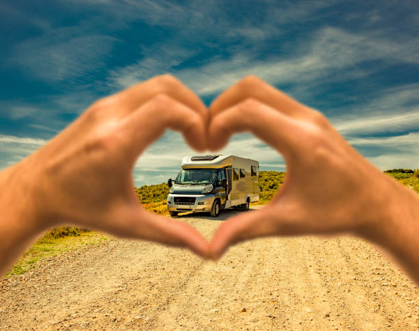 Motorhome on a dust road with a heart shaped human hand stock photo