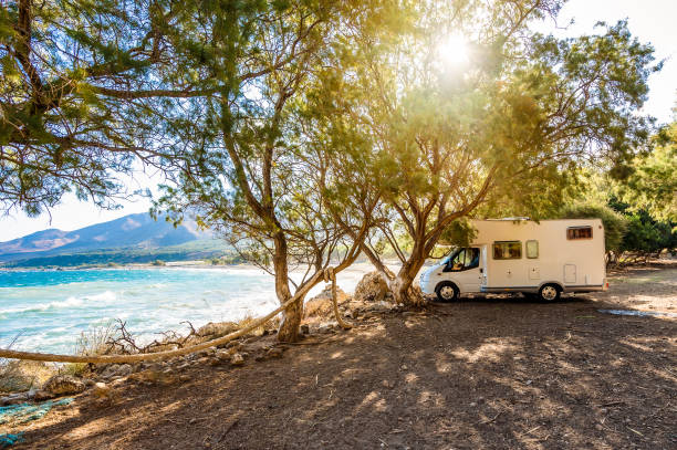 Motorhome RV parked on the beach under a tree facing the sea, Crete, Greece. stock photo