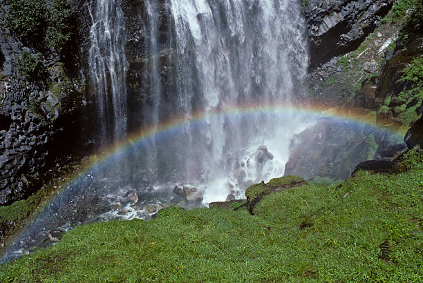 Rainbow Formed by a Waterfall Mount Rainier's numerous waterfalls are best viewed in early summer as melting snow feeds the streams, and again in autumn as the rains fill the streambeds. During late summer, only the major waterfalls will be flowing. Only a small number of the many waterfalls near Mount Rainier have been named. Whether the falls have names or not, they are a refreshing sight to both the eye and spirit. Narada Falls with its colorful rainbow were photographed near Paradise in Mount Rainier National Park, Washington State, USA. jeff goulden waterfall stock pictures, royalty-free photos & images