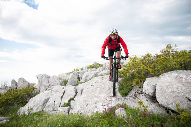Mountain biking A female biker is riding a bicycle over a rock in the mountain. georgijevic mountain biker stock pictures, royalty-free photos & images