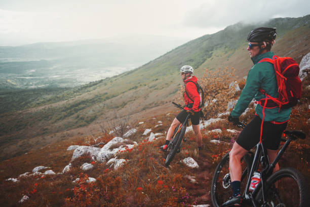 Mountain cycling Male and female bikers are having a ride through the rocky mountains. georgijevic mountain biker stock pictures, royalty-free photos & images