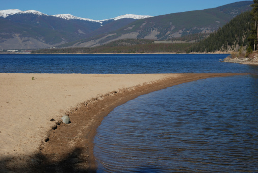 A curved sand spit formed in a mountain lake.