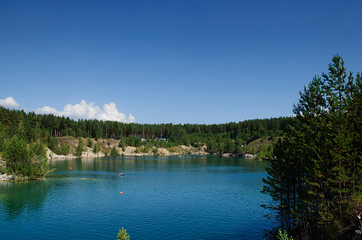 mountain lake in the summer at noon with vacationers and swimming tourists under the sun