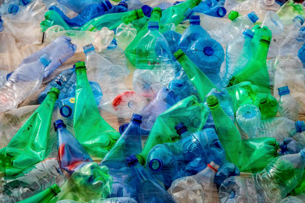 mountain of green and blue plastic bottles that are packed and bumped tightly together: a mountain of litter stock photo