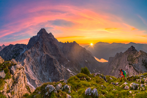 Mountain Photographer at glory sunrise with view to Watzmann and summit Cross of Mount Großer Hundstod