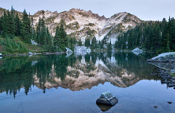 Mountain reflection in alpine lake Reflection of rugged mountain over still lake.  Late evening light.  alpine lakes wilderness stock pictures, royalty-free photos & images