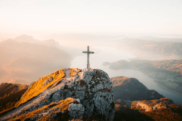 Mountain summit cross on alpine peak at sunset stock photo