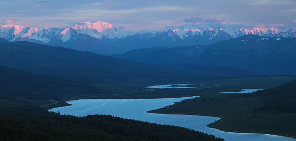 Mountain valley in the evening. Peaks in the sunset light, lake.