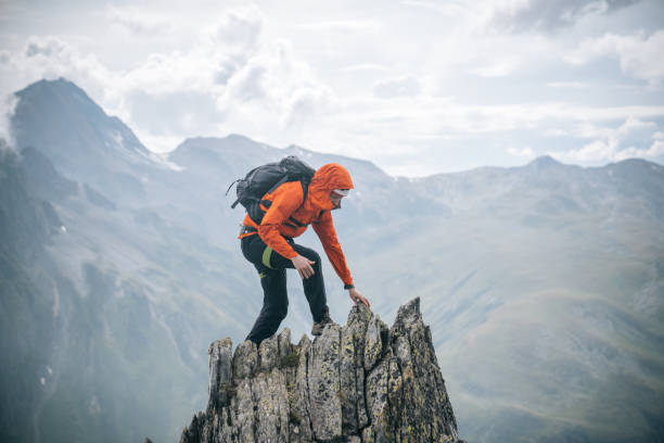 Mountaineer scrambles up summit of pinnacle stock photo