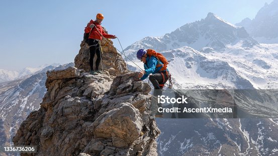 istock Mountaineering couple scramble to summit together 1336736206