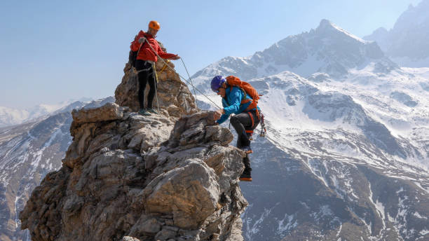 Mountaineering couple scramble to summit together stock photo