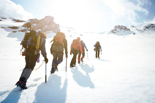 Group of mountaineers walking trough the mountains covered with snow.