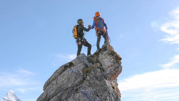 Mountaineers high five on mountain summit stock photo